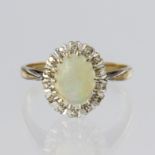 9ct yellow gold cluster ring featuring an oval opal cabochon measuring approx. 8mm x 6mm, surrounded