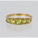 9ct yellow gold five stone graduated carved head ring set with round peridot stones, finger size