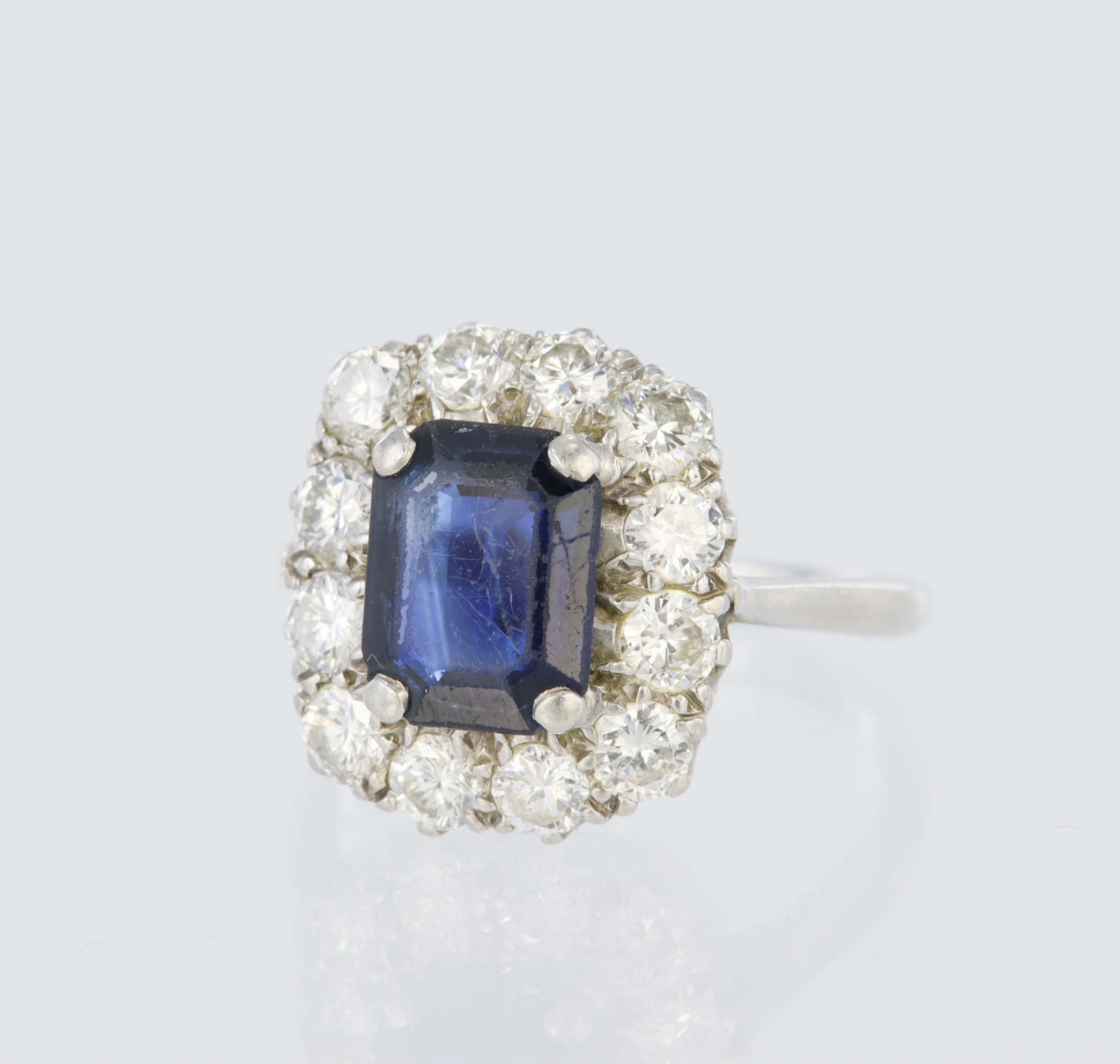 Platinum cluster ring set with a central rectangular step cut sapphire measuring approx. 9mm x