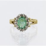 18ct yellow gold cluster ring featuring a central oval emerald measuring approx. 7mm x 5.5mm,