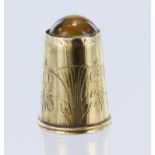 Yellow metal (tests as 18ct) thimble with "tigers eye" on top. Total weight 3.2g