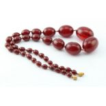 Amber ? bead necklace, comprising thirty-eight graduated polished oval cherry amber / bakelite ?