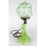 Art Deco green glass table lamp, depicting a lady sitting holding a polygon shade, approx 40cm high.