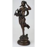 Bronze figure of a woman with basket. On a wooden base. Height measures approx 43cm.