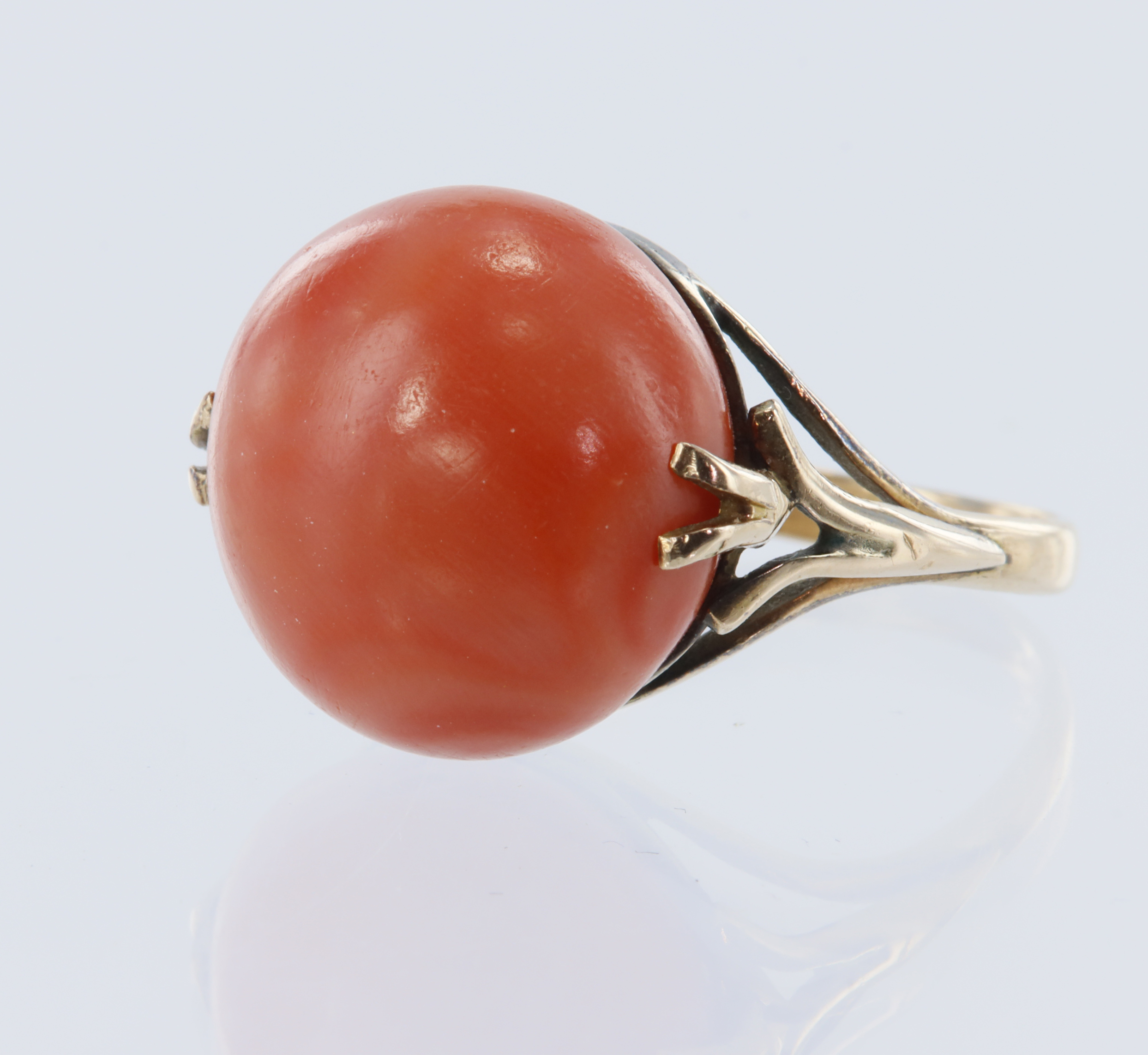 Yellow gold (tests 12ct) antique coral ring, circular coral cabochon measures 16mm, flanked with a