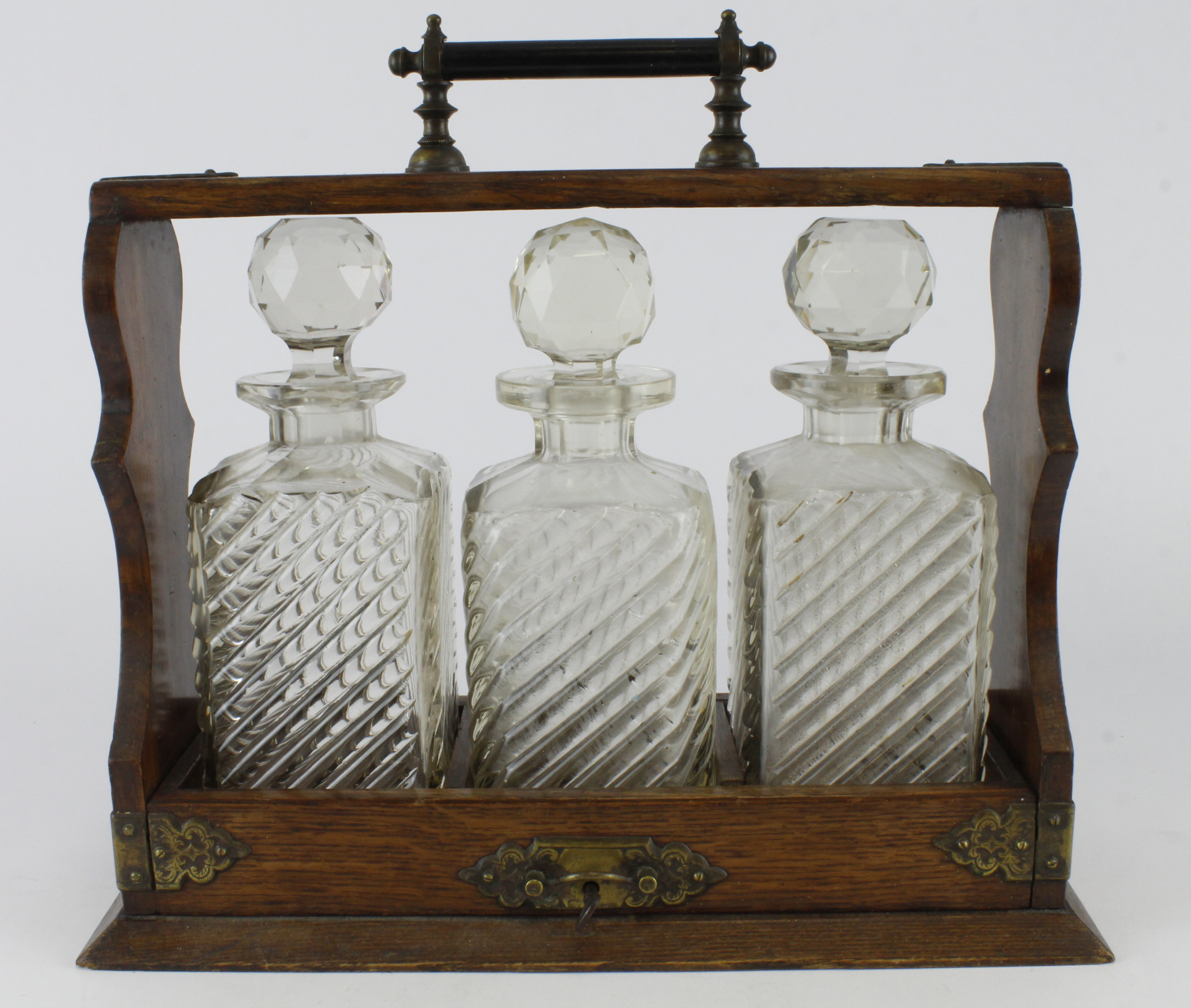 Oak tantalus, housing three cut glass decanters with stoppers, height 31.5cm approx., length 35cm