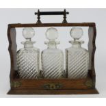 Oak tantalus, housing three cut glass decanters with stoppers, height 31.5cm approx., length 35cm