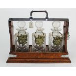 Oak tantalus, housing three cut glass decanters with stoppers (one decanter with loss), height 30