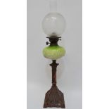 A late 19th century oil lamp with iron and copper patinated column support and opaque green glass