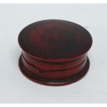 A late 19th century jeweller's carnelian polishing stone in circular turned treen case, diameter 3.