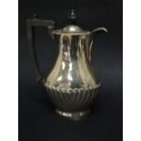 A silver hot water jug, the baluster body with gadrooned decoration with ebony finial and handle,