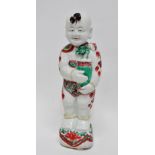 An 18th century Japanese Arita porcelain figure of a boy holding a vase with a lotus flower,