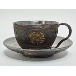 A late 19th/early 20th century Chinese carved wood and silver teacup and saucer, decorated with