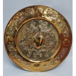 An Arts and Crafts style brass charger, the centre decorated an armorial, the border with roundels