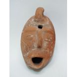 A Truscan style terracotta oil lamp, modelled as a mask, height 10cm.