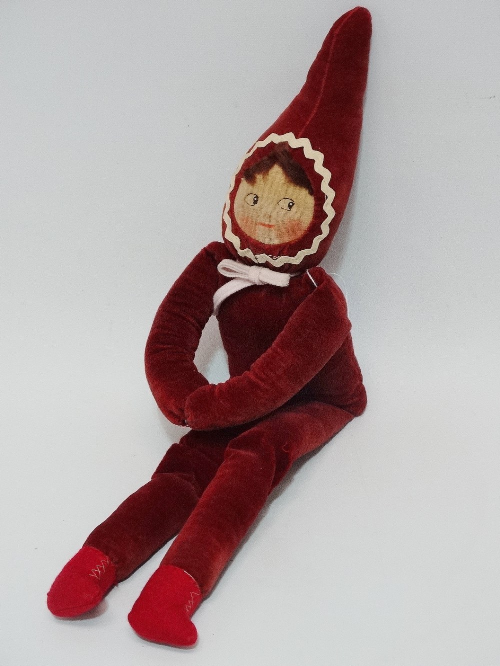 A early 20th century pixie doll in the manner of Norah Wellings, with plush maroon velvet body,