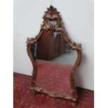 A carved giltwood wall mirror of Rococo design, height 110cm, width 62cm.