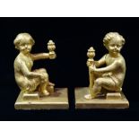 A pair of late 19th century cast iron gilt painted bookends, modelled as putti holding flaming