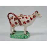 An early 19th century pottery cow creamer with lustre decoration, height 13.5cm.