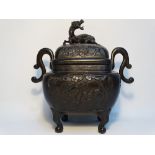 A late 19th century bronze twin handled koro, the cover surmounted with a dragon, the sides of the