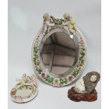 A late 19th/early 20th century German porcelain framed wall mirror surmounted by a pair of putti