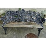 A cast iron garden bench, in Coalbrookdale style, the shaped back with fern decoration, with slatted