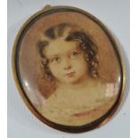 MINIATURE - An early 19th century oval miniature on card of a young girl, in a gold/yellow metal?