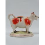 An early 19th century pottery cow creamer with sponged decoration, height 12cm.