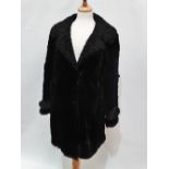 A ladies black faux fur coat with astrakhan collar and patterned silk lining, size 10/12, length