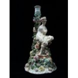 A late 19th/early 20th century German porcelain candlestick modelled as a maiden seated on a mound