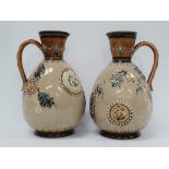 A pair of Doulton Lambeth stoneware ewers decorated with cartouches of carp, dragons and fruiting