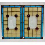 A pair of stained glass panels, decorated with blue, amber and amethyst roundels, centrally