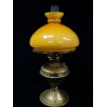 A brass oil lamp with an amber overlaid glass shade, height 50cm.
