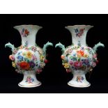 A pair of late 19th/early 20th century flower encrusted, twin handled Meissen vases, each with a
