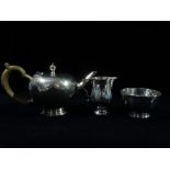 An early Georgian style silver three piece tea set, comprising a teapot, sugar bowl and milk jug,