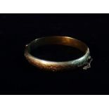 A 9ct gold hinged hollow bangle with engraved decoration, weight 13.2g approximately.