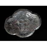 A silver dressing table tray of quatrefoil shape, relief embossed Raphael cherubs within clouds