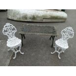 A green painted cast iron and wooden garden table with floral motifs, together with two white
