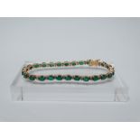 18ct gold, emerald and diamond tennis bracelet - A .750 gold tennis bracelet set twenty seven oval