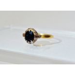 An 18ct gold ring set an oval sapphire, length 0.75cm, the shoulders set baguette diamonds, size N/