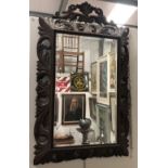 A late Victorian wall mirror - A carved and fretted oak surround bevel edged wall mirror with
