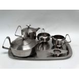 Robert Welch - A mid century stainless steel tea set, comprising a teapot, tea strainer, hot water