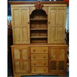 A stripped pine dresser with open three drawer centre flanked by two cupboard doors with three short