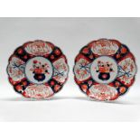 A pair of Japanese Imari footed dishes, with petal shaped rim and decorated with panels showing a