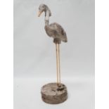 A reconstituted stone garden ornament modelled as a stork with yellow painted metal legs on a