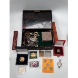 A tin containing tokens, coins, napkin rings, a lighter, penknife and other miscellaneous items.