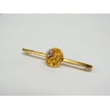 A 9ct. hallmarked bar brooch set a diamond of 0.4ct approximately, mounted on a gold nugget and