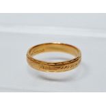 A 22ct gold wedding band with engraved decoration, weight 3.5g.