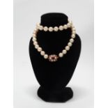 A freshwater pearl necklace with 9ct gold ornate clasp with red stone and seed pearl decoration,