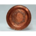 Hugh Wallis Arts and Crafts copper - An embossed copper charger with floral and foliate chaplet,